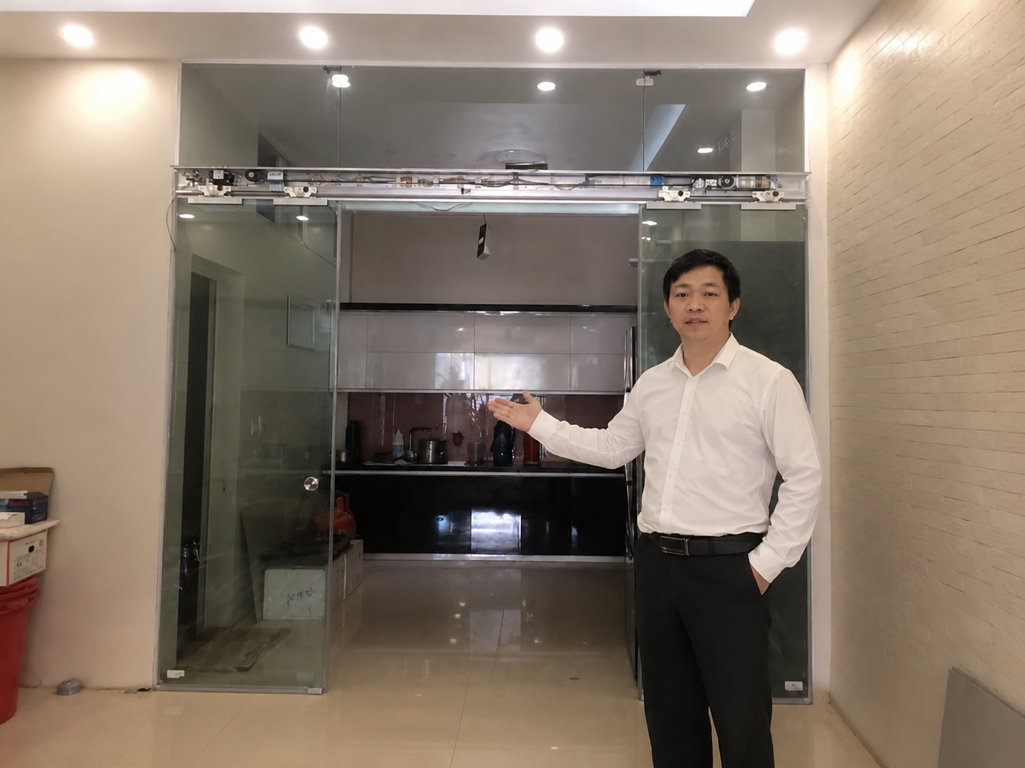 Cửa kính trượt tự động phòng bếp trong nhà, người đàn ông đứng giới thiệu hệ thống cửa